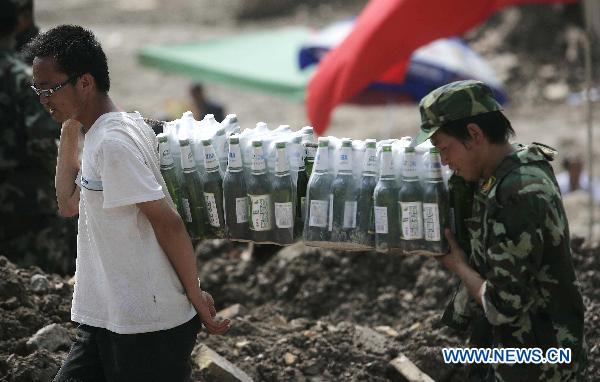 Two rescuers carry relief materials on a street torn by mudslides in Zhouqu County, Gannan Tibetan Autonomous Prefecture in northwest China's Gansu Province, Aug. 10, 2010. 