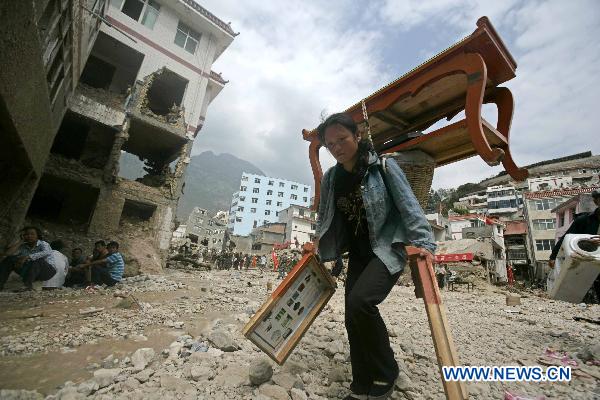 A moman carries her properties on a street torn by mudslides in Zhouqu County, Gannan Tibetan Autonomous Prefecture in northwest China's Gansu Province, Aug. 10, 2010. 