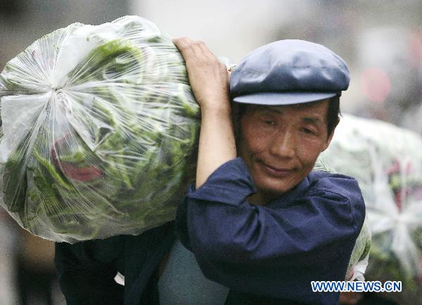 A resident carries relief materials on a street torn by mudslides in Zhouqu County, Gannan Tibetan Autonomous Prefecture in northwest China's Gansu Province, Aug. 10, 2010. 