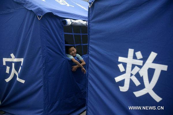 A boy looks out of a disaster relief tent at the No.3 Middle School in Zhouqu County, Gannan Tibetan Autonomous Prefecture in northwest China's Gansu Province, Aug. 10, 2010.