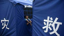 A boy looks out of a disaster relief tent at the No.3 Middle School in Zhouqu County, Gannan Tibetan Autonomous Prefecture in northwest China's Gansu Province, Aug. 10, 2010.