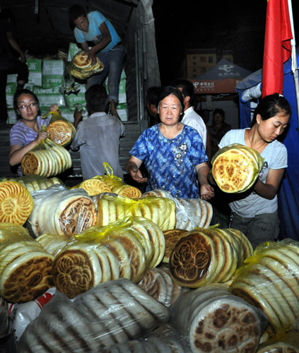 Residents of Zhouqu County receive pancakes from the provincial government, Aug 11, 2010. 36,206 large Chinese pancakes and 61 boxes of pickles, ordered by Gansu provincial department of civil affairs, arrived at the landslide-hit county of northwest China's Gansu Province early Wednesday morning. 