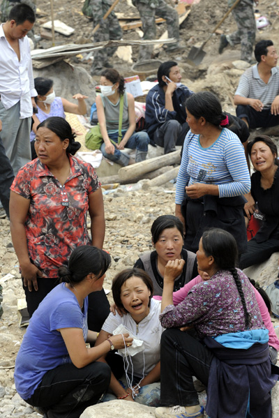 Local residents wait on ruins and wish for good news of their missing beloved ones in the landslides-hit Zhouqu County, Gannan Tibetan Autonomous Prefecture in northwest China's Gansu Province, Aug. 11, 2010.