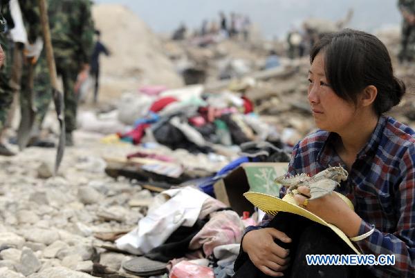 Hui Guoqin holding her father&apos;s belongings waits on ruins and wish for the good news of her missing parents and sister-in-law in the landslides-hit Zhouqu County, Gannan Tibetan Autonomous Prefecture in northwest China&apos;s Gansu Province, Aug. 11, 2010.