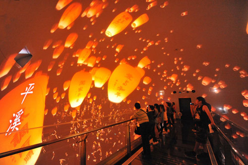 Tourists look at a film featuring sky lanterns inside the Taiwan Pavilion at the Shanghai Expo Site, August 10, 2010.