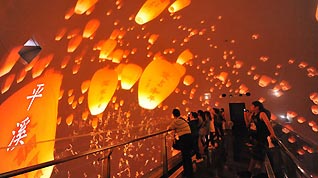 Tourists look at a film featuring sky lanterns inside the Taiwan Pavilion at the Shanghai Expo Site, August 10, 2010.