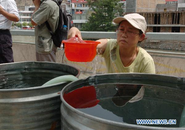 A woman takes purified water in Zhouqu County, Gannan Tibetan Autonomous Prefecture in northwest China&apos;s Gansu Province, Aug. 11, 2010.