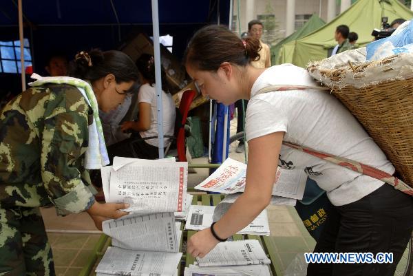 A post staff member distributes newspapers to residents for free in the camp post office set up in the landslides-hit Zhouqu County, Gannan Tibetan Autonomous Prefecture in northwest China&apos;s Gansu Province, Aug. 11, 2010.