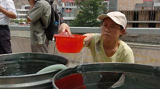 A woman takes purified water in Zhouqu County, Gannan Tibetan Autonomous Prefecture in northwest China's Gansu Province, Aug. 11, 2010.