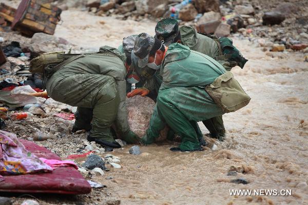 Four soldiers carry a big stone out of river channel in Zhouqu County, Gannan Tibetan Autonomous Prefecture in northwest China's Gansu Province, Aug. 12, 2010.