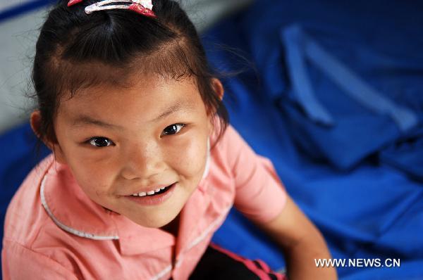 Seven-year-old Liu Hui plays in a tent at a temporary shelter place in landslide-hit Zhouqu County, Gannan Tibetan Autonomous Prefecture in northwest China&apos;s Gansu Province, Aug. 12, 2010.