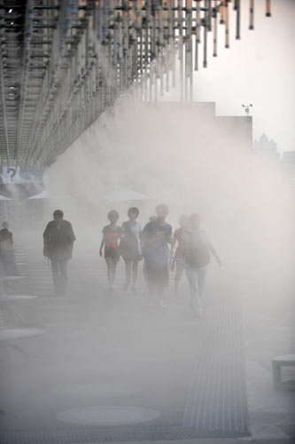 Visitors walk through water mists in front of the Shanghai Corporate Pavilion at Expo Park in Shanghai, Aug 12, 2010.