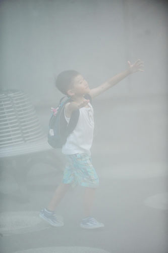 A child plays in the water mists in front of the Shanghai Corporate Pavilion at Expo Park in Shanghai, Aug 12, 2010.