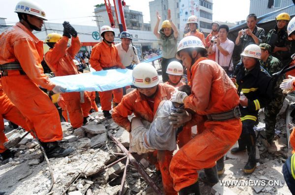 Rescuers carry an injured child just saved from a building collapse site in Qiaoxu Town of Guigang, a city of southwest China's Guangxi Zhuang Autonomous Region, Aug. 13, 2010. A three-story building in Qiaoxu Town partly collapsed on Friday morning, with many residents trapped inside, Local officials said. (Xinhua/Li Bin) (zn) 