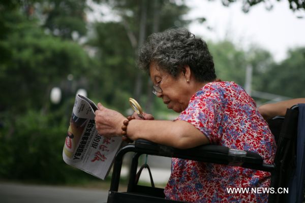 An elderly woman reads a newspaper at a park in Beijing, capital of China, Aug. 13, 2010. China has 169 million citizens aged over 60, accounting for 12.5 percent of its total population. The figure would climb up to 31 percent by 2050, said Li Baoku, president of China Aging Development Foundation (CADF), on Wednesday. 