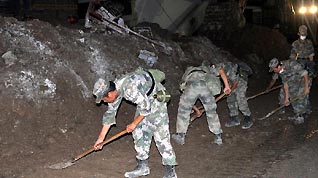 Soldiers clear road surface in landslide-hit Zhouqu County, northwest China's Gansu Province, early Aug. 13, 2010.