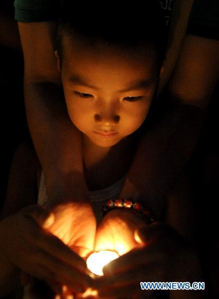 A boy lights up candles during a mourning activity in Shijiazhuang, capital of north China's Hebei Province, Aug. 15, 2010, to mourn for the victims of the Aug. 8 mudslide disaster in Zhouqu County, Gannan Tibetan Autonomous Prefecture in northwest China's Gansu Province.