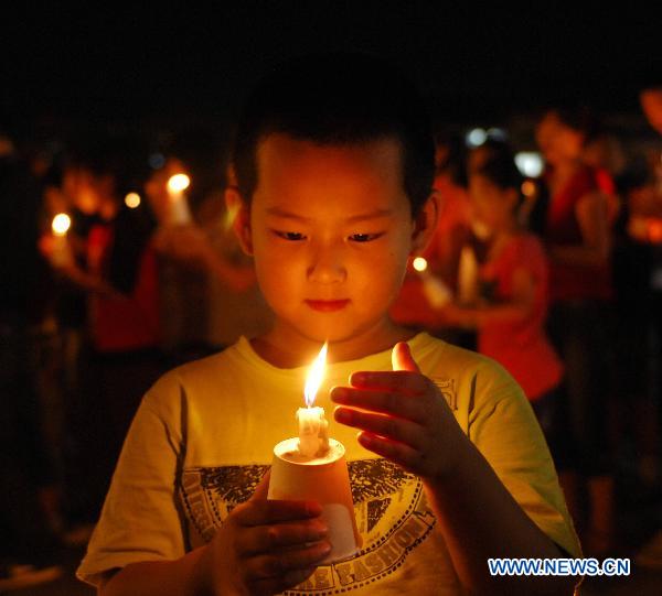 A boy lights up candles during a mourning activity in Changchun, capital of northeast China's Jilin Province, Aug. 15, 2010, to mourn for the victims of the Aug. 8 mudslide disaster in Zhouqu County, Gannan Tibetan Autonomous Prefecture in northwest China's Gansu Province.