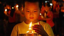 A boy lights up candles during a mourning activity in Changchun, capital of northeast China's Jilin Province, Aug. 15, 2010, to mourn for the victims of the Aug. 8 mudslide disaster in Zhouqu County, Gannan Tibetan Autonomous Prefecture in northwest China's Gansu Province.