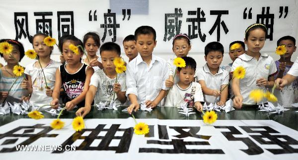 Children present flowers during a mourning activity in Changsha, central China's Hunan Province, Aug. 15, 2010, to mourn for the victims of the Aug. 8 mudslide disaster in Zhouqu County, Gannan Tibetan Autonomous Prefecture in northwest China's Gansu Province. 