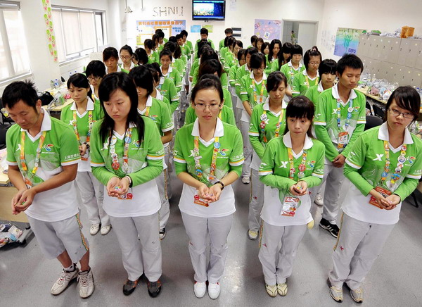 Volunteers at Shanghai World Expo observe a moment's silence in tribute to the victims in the Zhouqu mudslide disaster in northwest China's Gansu Province on August 15, 2010.