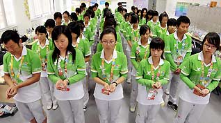 Volunteers at Shanghai World Expo observe a moment's silence in tribute to the victims in the Zhouqu mudslide disaster in northwest China's Gansu Province on August 15, 2010.