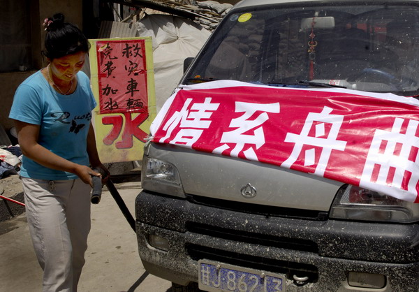 A woman is ready to wash a car carrying relief materials for mudslide-hit Zhouqu in Minxian County, northwest China&apos;s Gansu Province, Aug 14, 2010.
