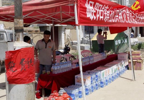 Volunteers provide free drinking water for vehicles carrying relief materials for mudslide-hit Zhouqu at a stop in Minxian County, northwest China&apos;s Gansu Province, Aug 14, 2010. 