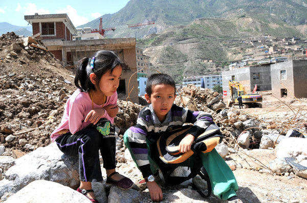 Wang Jinyan, 8, and her brother, Wang Jinhong, 10, sit in front of the ruins of their school building, worrying that they cannot go to school again. They are students from No 1 Primary School in mudslide-hit Zhouqu, northwest China's Gansu Province. 