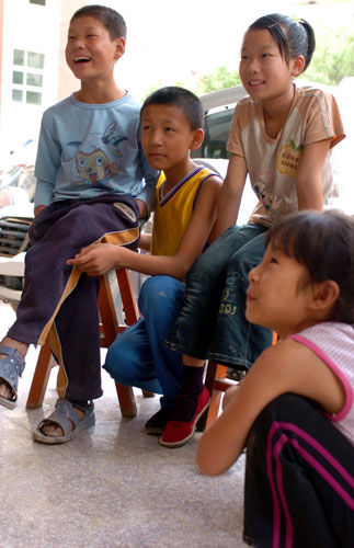 Children watch TV programs outside their settlement in mudslide-hit Zhouqu, northwest China's Gansu Province.