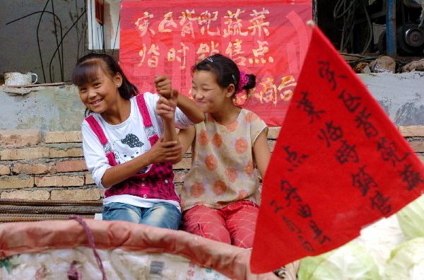 Two girls play as they sell vegetables in landslide-hit Zhouqu County, Gannan Tibetan Autonomous Prefecture in northwest China's Gansu Province, Aug. 16, 2010.