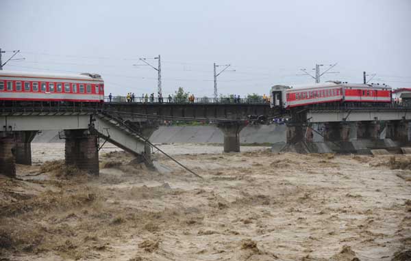Two carriages of a passenger train fell into a river after floods destroyed a bridge in Guanghan, Sichuan province, August 19, 2010. 