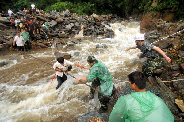 Rescuers help a tourist cross a riptide at Huilong Village, Bali Town of Xinxiang, central China's Henan Province, Aug. 19. 2010.