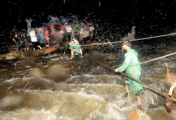 A rescuer carries a tourist across a riptide at Huilong Village, Bali Town of Xinxiang, central China's Henan Province, Aug. 19. 2010. 