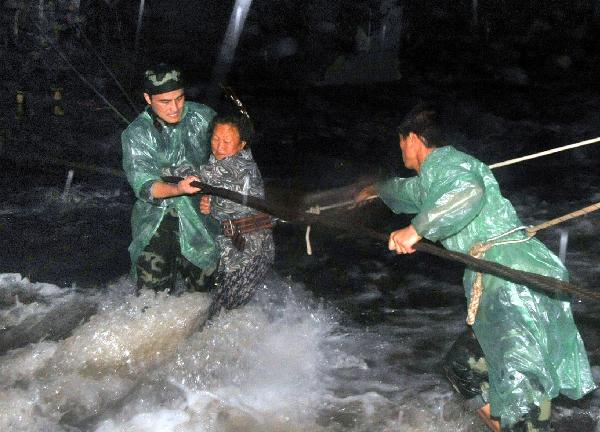 Rescuers help a tourist cross a riptide at Huilong Village, Bali Town of Xinxiang, central China's Henan Province, Aug. 19. 2010.