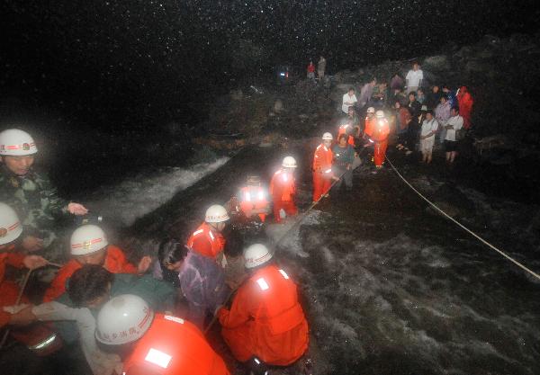 Rescuers help a tourist cross a riptide at Huilong Village, Bali Town of Xinxiang, central China's Henan Province, Aug. 19. 2010.