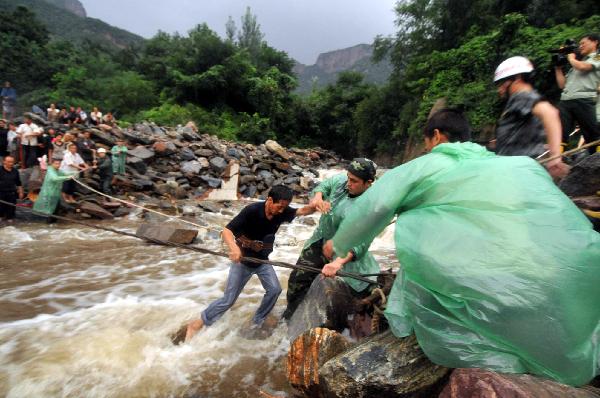 Rescuers help a tourist cross a riptide at Huilong Village, Bali Town of Xinxiang, central China's Henan Province, Aug. 19. 2010.