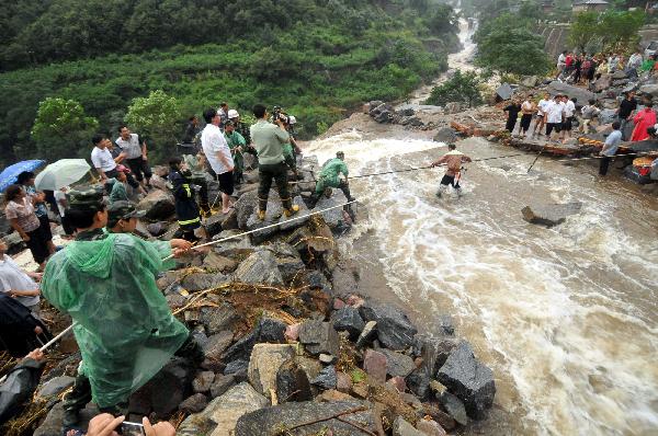 Rescuers help a tourist cross a riptide at Huilong Village, Bali Town of Xinxiang, central China's Henan Province, Aug. 19. 2010. 