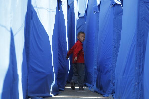 A boy plays between tents in the landslide-hit Zhouqu County, Gannan Tibetan Autonomous Prefecture in northwest China's Gansu Province, Aug. 19, 2010.