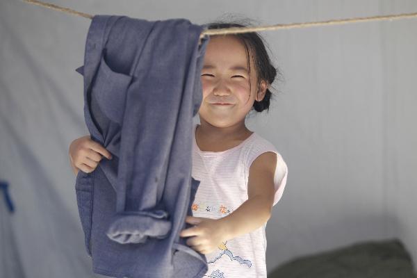 A girl arranges her father's clothes in a tent in the landslide-hit Zhouqu County, Gannan Tibetan Autonomous Prefecture in northwest China's Gansu Province, Aug. 19, 2010. 