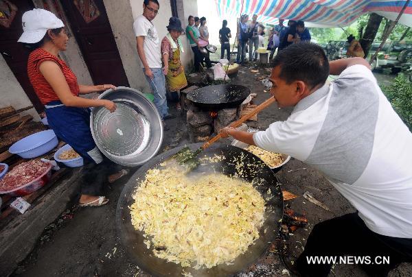 People make dinner at a temporary shelter in the mudslide-hit Puladi Township of Gongshan Drung-Nu Autonomous County, southwest China's Yunnan Province, Aug. 20, 2010. 