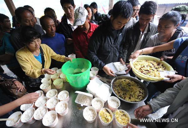 People queue for dinner at a temporary shelter in the mudslide-hit Puladi Township of Gongshan Drung-Nu Autonomous County, southwest China&apos;s Yunnan Province, Aug. 20, 2010.