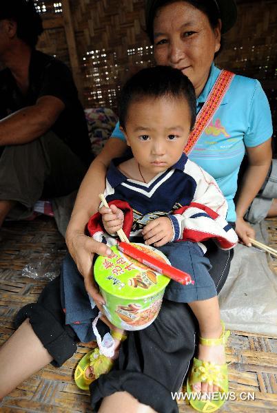 A mother and a son are ready for dinner at a temporary shelter in the mudslide-hit Puladi Township of Gongshan Drung-Nu Autonomous County, southwest China&apos;s Yunnan Province, Aug. 20, 2010. 