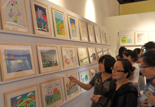 A girl takes photos of drawings created by autistic children at Swedish Pavilion in the World Expo park in Shanghai, east China, Aug. 20, 2010. Autistic children from China and Singapore will display their works in Swedish Pavilion and UK Pavilion for nearly three weeks.