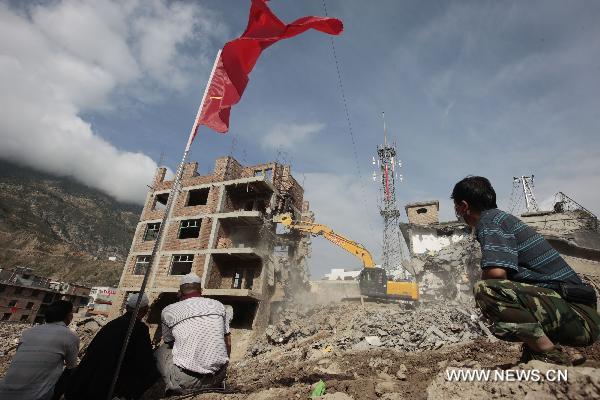 Residents viewing a crane demolishing a dilapidated building at the mudslide-hit Zhouqu County, Gannan Tibetan Autonomous Prefecture in northwest China&apos;s Gansu Province, Aug. 20, 2010.