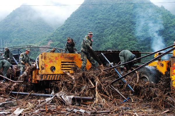 Soldiers clear a vehicle covered by junks in Chengxian County of Longnan City, northwest China's Gansu Province, Aug. 20, 2010. Landslides and mudslides occurred in the city due to the heavy rains from Aug. 11. Twenty-three people were reported killed.