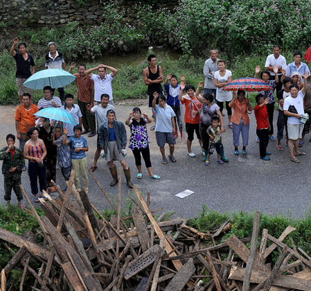 Villagers wave to soldiers who drop food above on two helicopters in Hushan County, Dandong on August 22, 2010.