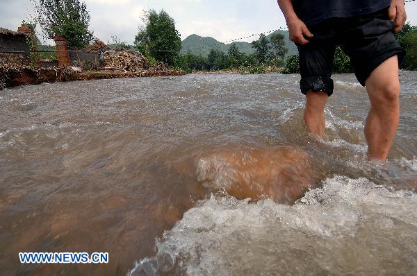 A villager walks in flooded road at Tuanjie Village, Kuandian Man Autonomous County of Dandong City, northeast China's Liaoning Province, Aug. 21, 2010.