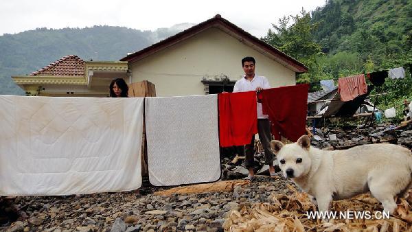 A couple air their belongings at Yanjing Village of Qingping Township in Mianzhu City, southwest China's Sichuan Province, Aug. 21, 2010.