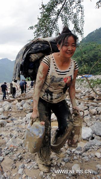 A resident of Yanjing Village carries useful belongings from her destroyed home to a temporary shelter in mudslides-hit Qingping Township of Mianzhu City, southwest China's Sichuan Province, Aug. 21, 2010. 